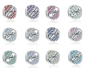 May include: Twelve silver charm beads, each representing a month. Each bead has a band with the month's name and is decorated with colourful, sparkling crystals. The crystals are arranged in a pattern around the band, offering a touch of elegance.