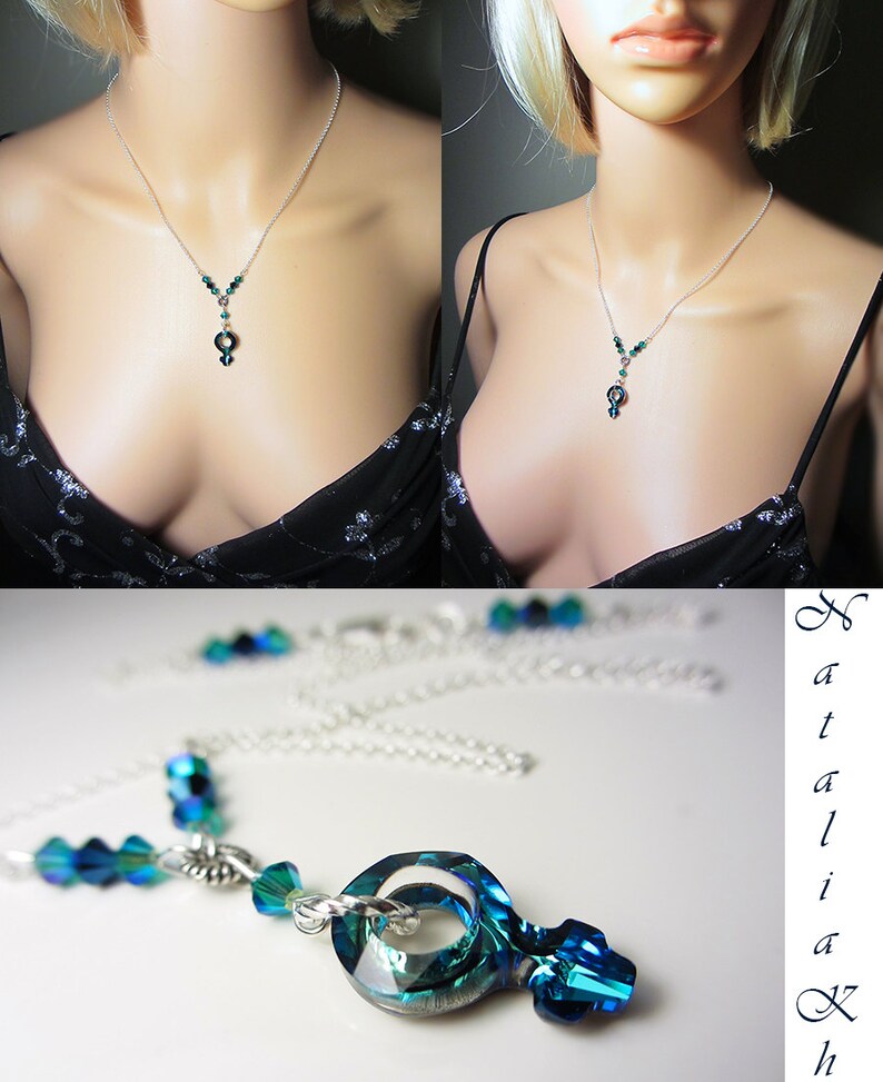 May include: A silver chain necklace with a teardrop-shaped pendant made of faceted green and blue crystals. The pendant is a stylized female symbol.