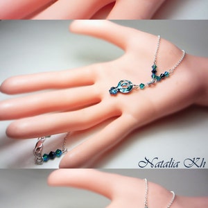 May include: A silver chain necklace with a blue crystal pendant in the shape of a treble clef. The necklace has smaller blue crystals along the chain.