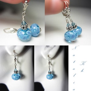 Pu&ograve; includere: Orecchini in vetro azzurro con un design a spirale. Gli orecchini hanno dettagli in metallo color argento e una chiusura a leva. Gli orecchini sono mostrati in pi&ugrave; viste, tra cui un primo piano e su un manichino.