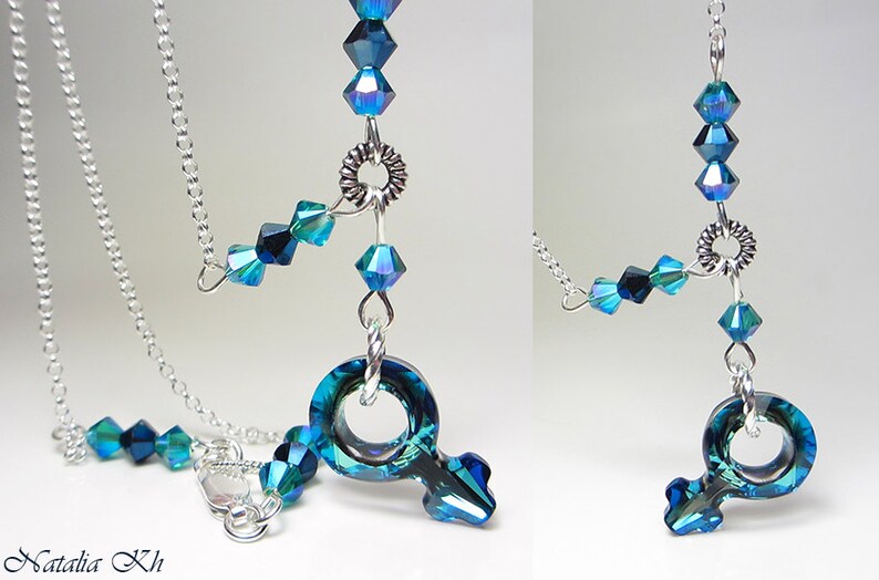 May include: A silver chain necklace with a blue crystal pendant in the shape of the female gender symbol. The pendant is surrounded by smaller blue crystals.