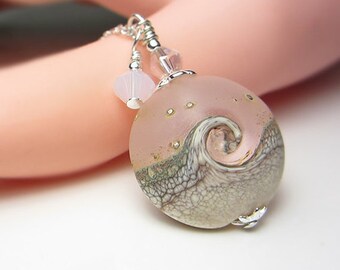 May include: A silver necklace with a pink and white glass pendant featuring a swirling wave design. The pendant has a textured surface and gold flecks.