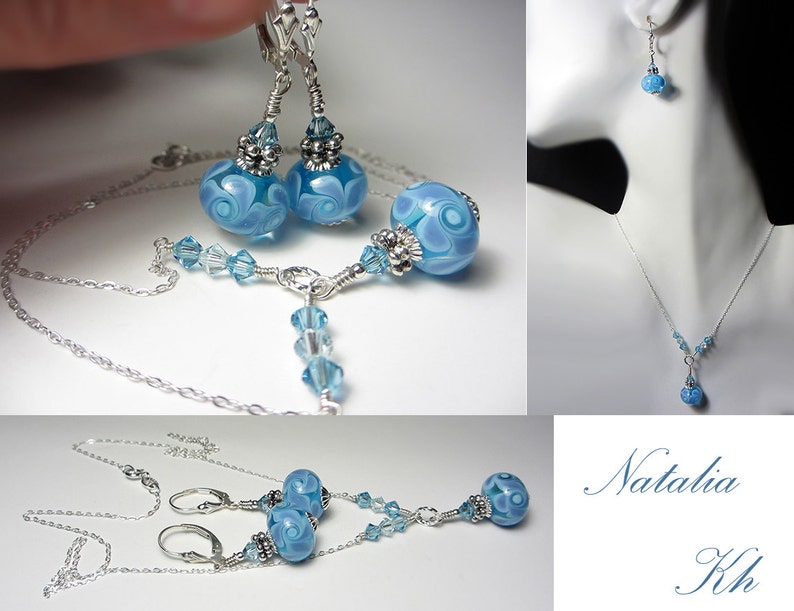 May include: A jewelry set featuring a necklace and earrings. The set includes a silver chain necklace with a blue glass bead pendant and matching earrings. The earrings and pendant have a swirl design. The set is displayed on a white background.