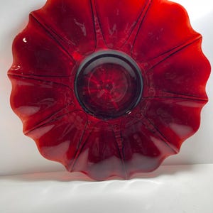 Op de afbeelding: Een grote, rode glazen serveerschaal met een gegolfde rand. De schaal is gemaakt van helder glas met een diepe rode tint.
