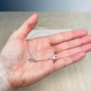May include: A silver wire loop with two small silver rings at the ends. The wire loop is about 3 inches in diameter.
