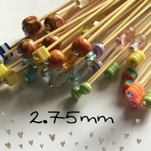 Puede incluir: Un conjunto de brochetas de bambú decorativas con cuentas coloridas y estampadas. Las cuentas presentan varios diseños, incluyendo rayas, cuadrados y patrones veteados. El texto "2,75mm" es visible.