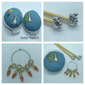 May include: Two blue fabric pincushions with Peter Rabbit designs, a set of two silver rabbit needle minders, and a set of five carrot stitch markers.