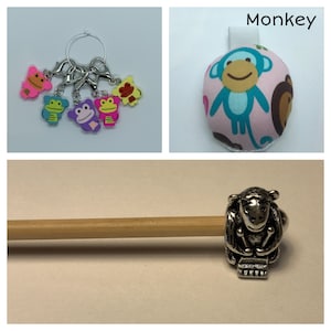 May include: A set of five colorful monkey stitch markers, a pink and blue monkey pincushion with the word "Monkey" above it, and a silver monkey stitch marker on a wooden knitting needle.