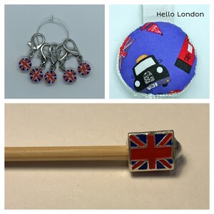 May include: Set of five silver stitch markers with red, white, and blue Union Jack designs. The markers are attached to a silver ring. A wooden knitting needle with a silver Union Jack charm is also shown. The image includes the text "Hello London".