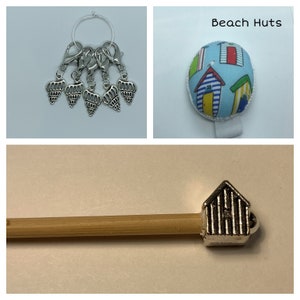 May include: Set of five silver seashell stitch markers with a silver ring, a blue and white beach hut pincushion, and a wooden knitting needle with a silver beach hut end cap.