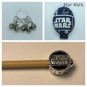 May include: Four silver stitch markers with green and black camouflage beads. A silver stitch marker with a round, black and silver Star Wars logo charm is attached to a wooden knitting needle.