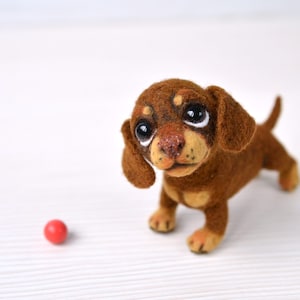 Naaldvilten teckelpuppy. Kleine vilten hond. Lief dier. Grappig speelgoed. Leuk speelgoedje. Klein hondje voor pop. Blythe-huisdier.
