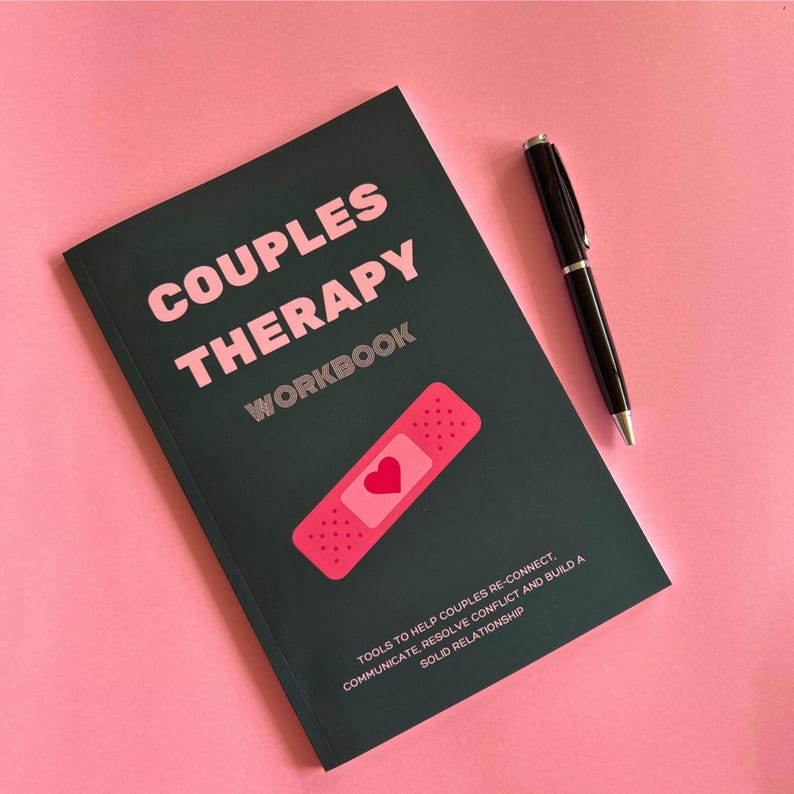 May include: A dark green couples therapy workbook with a pink plaster with a heart on it. The text on the cover reads "Couples Therapy Workbook" and "Tools to help couples re-connect, communicate, resolve conflict and build a solid relationship."