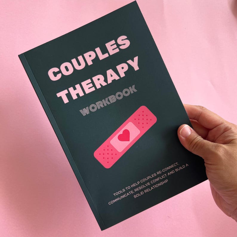 May include: A dark green couples therapy workbook with a pink bandage and heart graphic. The text on the cover reads "Couples Therapy Workbook" and "Tools to help couples re-connect, communicate, resolve conflict and build a solid relationship."