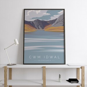 May include: A framed poster featuring a minimalist illustration of a mountain range and a lake. The poster is titled "Cwm Idwal - Snowdonia".