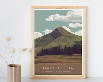 May include: A framed illustration of a mountain range with a blue sky and white clouds. The mountain range is green and brown with a forest of dark green trees at the base. The text "MOEL HEBOG - ERYRI" is printed at the bottom of the illustration.