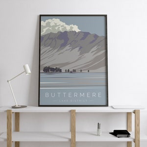 May include: A minimalist poster with a blue and grey illustration of a mountain range and a lake. The text "BUTTERMERE - LAKE DISTRICT -" is at the bottom of the poster.