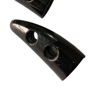 May include: Three black plastic toggle clasps with two holes each. The clasps are shaped like a pointed tooth.