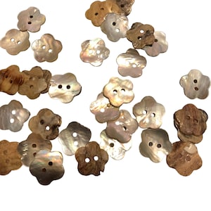 May include: A collection of 20 flower-shaped buttons made from natural shell. The buttons are in shades of brown, white, and iridescent.