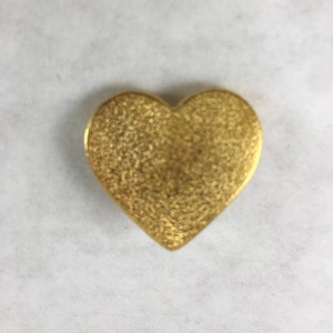 May include: A gold heart-shaped pendant with a textured surface.