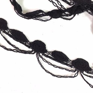May include: Black beaded trim with multiple layers and a scalloped edge. The trim is made of small, round beads that are strung together in a continuous pattern.