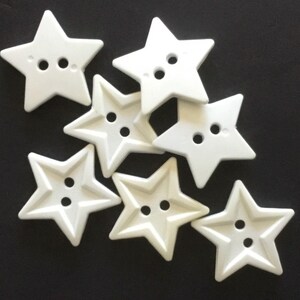 May include: Eight white plastic star-shaped buttons with two holes each.