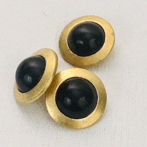 May include: Three gold-toned buttons with black centers. The buttons have a raised, rounded design.