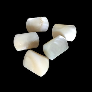 May include: Five white mother of pearl buttons with a rounded rectangular shape.