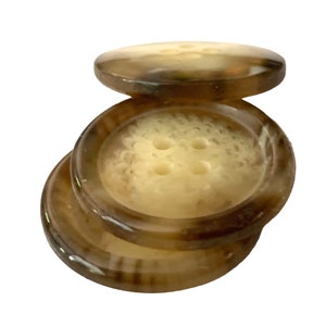 May include: Four brown and cream colored buttons with four holes each. The buttons have a textured surface and a slightly raised edge.