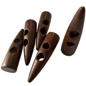 Op de afbeelding: Vijf bruine houten knopen met elk twee gaten. De knopen zijn aan de ene kant puntig en aan de andere kant rond.
