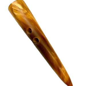 May include: A brown and gold horn button with two holes. The button is pointed at one end and rounded at the other.