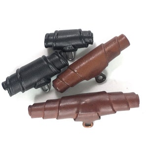 May include: Three leather buttons, two brown and one black, with a spiral design. The buttons have a metal loop for attaching to clothing.