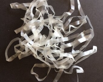 May include: A pile of clear elastic bands, also known as rubber bands, on a dark gray surface.