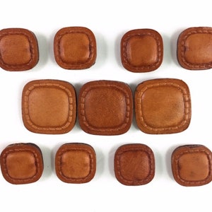 May include: Ten brown leather square buttons with a stitched border.