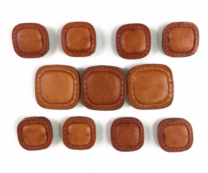 May include: Ten brown leather square buttons with a stitched border.
