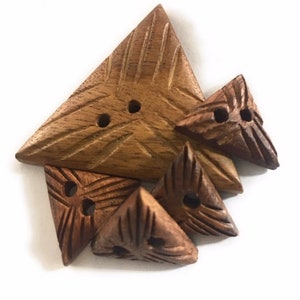 May include: Five wooden triangle buttons with two holes each. The buttons are carved with a geometric pattern and have a natural brown color.
