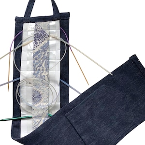 May include: A denim blue knitting needle case with a quilted center panel featuring a blue and white paisley pattern. The case holds various knitting needles, including circular and straight needles. The case is open, revealing the contents.