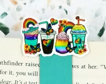 May include: A teal bookmark with a colorful design of rainbow-themed beverages. The bookmark features a series of illustrated drinks with rainbows, hearts, and flowers. The text "JustAddJewelry" is also visible.