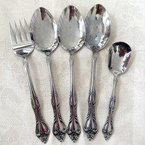 May include: Set of five silver-plated utensils, including a fork, two spoons, a slotted spoon, and a small spoon. The utensils have ornate handles with a floral design.
