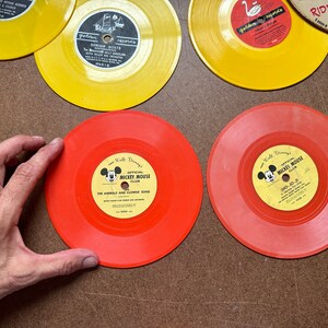 May include: Two red vinyl records with yellow labels featuring Mickey Mouse and the text "Walt Disney's Official Mickey Mouse Club". One record has the text "The Animals and Clown's Song" and the other has the text "CHO-10-24".