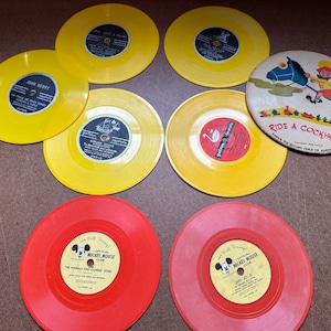 May include: A collection of ten vintage yellow and red vinyl records. The records feature various children's songs, including "Ride a Cockhorse" and "The Animals and Johnny Song".