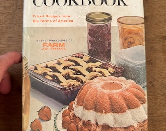 May include: Vintage cookbook titled "Freezing & Canning COOKBOOK" with images of preserved foods and baked goods. The cover features a cake with strawberries, a pie, and jars of preserves. Published by the Food Editors of Farm Journal.