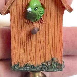 Darling lampbloemknop in de vorm van een vogelhuisje met uitspringende vogel