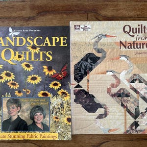 Op de afbeelding: Twee quiltboeken, een met de titel "Landscape Quilts" met een bloemmotief op de omslag en de andere met de titel "Quilts from Nature" met een vogelmotief op de omslag.