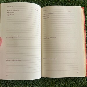 May include: Open recipe book with lined pages. The book is open to a spread with prompts for recipe details: recipe name, kitchen source, favorite ingredients, oven/range directions, and microwave instructions. The book's cover is red.