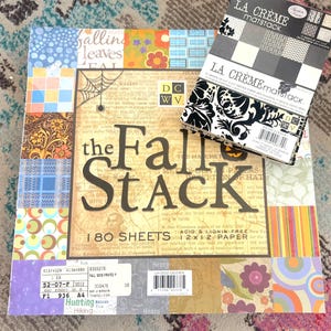 May include: A large square paper pad titled The Fall Stack with 180 sheets of 12 x 12 inch paper, featuring various colorful patterns, alongside a smaller La Crème Matstack paper pad containing 72 sheets of 4.5 x 6.5 inch flocked paper.