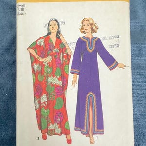 May include: Simplicity sewing pattern number 5315 for a long, flowing dress with a V-neck and long sleeves. The pattern includes two different styles: one with a floral print and the other in a solid purple colour. The pattern is for sizes 8-10.