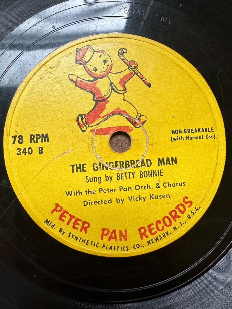 May include: A yellow vinyl record with a gingerbread man illustration. The record is labeled "The Gingerbread Man" and features the text "Sung by Betty Bonnie" and "Peter Pan Records".