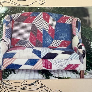 May include: A patchwork loveseat with a high back and armrests. The upholstery features a mix of red, white, and blue patterned fabrics, including gingham, floral, and striped designs. The wooden legs provide a sturdy base.