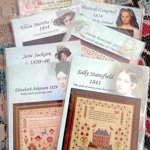 May include: A collection of cross-stitch patterns and kits, featuring portraits and historical designs. The kits include framed samplers with floral and architectural motifs, and text. The names and dates on the kits include: Maria Lariccha 1837, Eliza Linfoot 1834, and Sally Stansfield 1841.